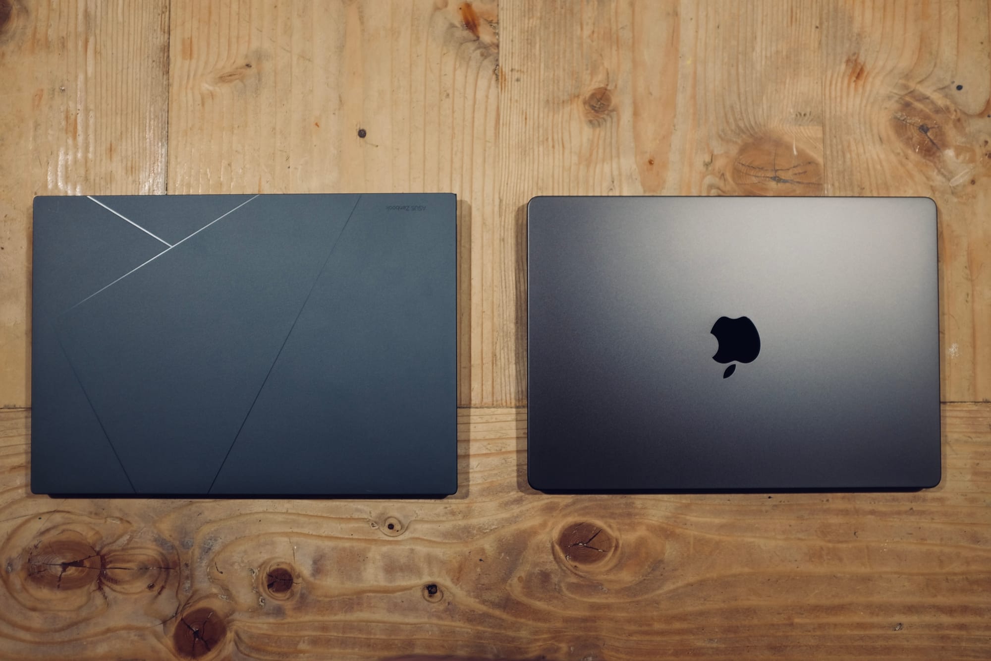 Asus Zenbook and MacBook Pro on wooden table.